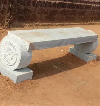 A long granite bench with a carved floral support at Gomateshwara.
