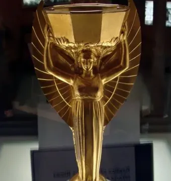 Jules Rimet Trophy replica with a winged female figure holding a cup overhead on a dark base.