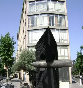Monument to Narcís Monturiol with a bronze submarine model on a dark geometric pedestal beside a city street.