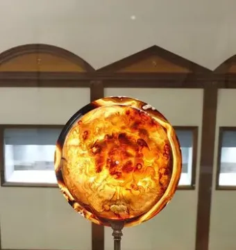 The Tazza Farnese, a translucent amber-and-orange carved cameo bowl on a silver stand in a museum setting.