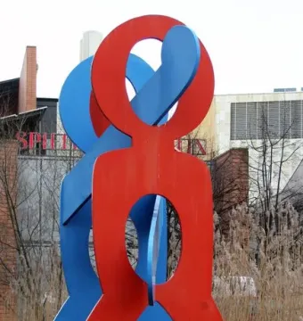 The Boxers sculpture by Keith Haring, showing two brightly colored stylized figures on a dark base near water.