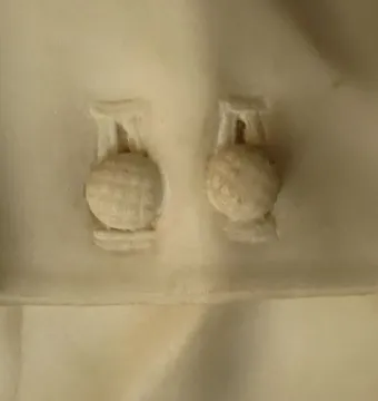 Close-up of two intricately carved spherical elements set in a light surface recess.