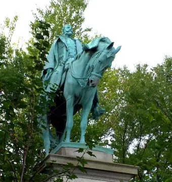 Charles Devens statue, a green-patinated bronze equestrian sculpture on a stone pedestal framed by trees.