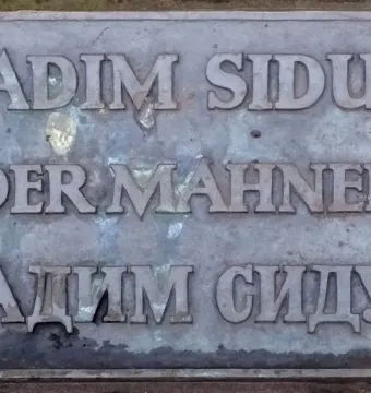 Bronze plaque for Der Mahner by Vadim Sidur with raised Latin and Cyrillic lettering.