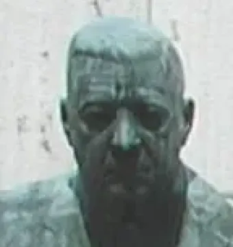 Weathered green-patina bust in the Polio Hall of Fame showing a man’s head and shoulders against a plain background.