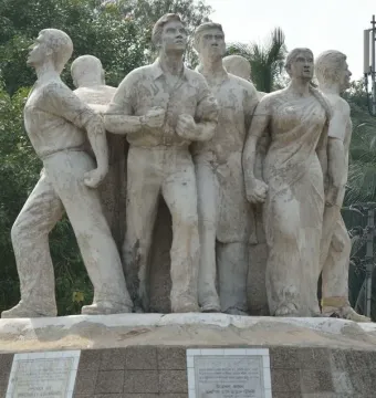 Anti Terrorism Raju Memorial Sculpture with several figures in dynamic poses, set on a base with plaques and trees behind it