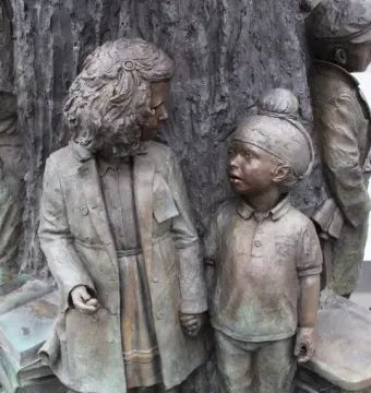 Bronze children figures beside the textured tree trunk of the Betty Campbell statue.