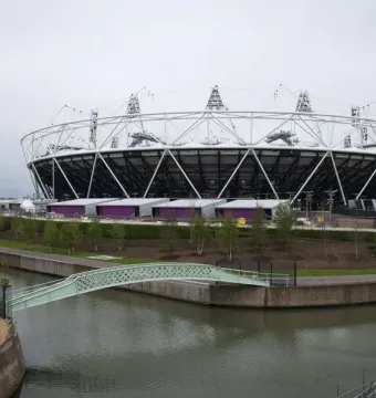 The Orbit Tower rises in a twisting reddish-brown steel structure against a bright overcast sky.