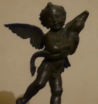 Bronze putto with a dolphin, the winged child poised on one foot atop a small base.