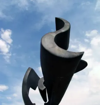 Ayrton Senna Monument bronze sculpture silhouetted against a blue sky with wispy clouds.