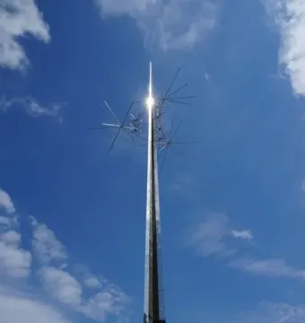 Ad Astra sculpture with a tall metallic spire and radiating spikes against a blue sky.