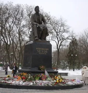 Chekhov Monument with a seated bronze statue on a stone pedestal in a snowy park