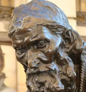 Dark bronze bust of Eustache de Saint Pierre showing an elderly bearded man in a cap looking downward.