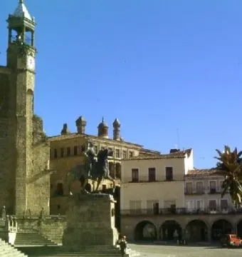 Francisco Pizarro equestrian statue on a stone pedestal in a town square beside a large stone church tower.