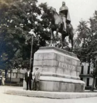 George Armstrong Custer monument with a horse and rider atop a multi-tiered stone pedestal, with two people standing nearby.