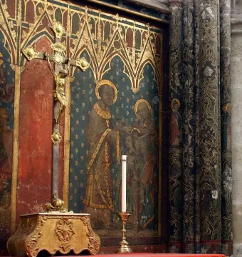 Gero Cross crucifix with a gilded Christ figure on a dark cross before a painted religious mural.