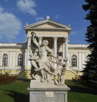 Laocoön sculpture of three figures entangled with serpents on a tall stone pedestal