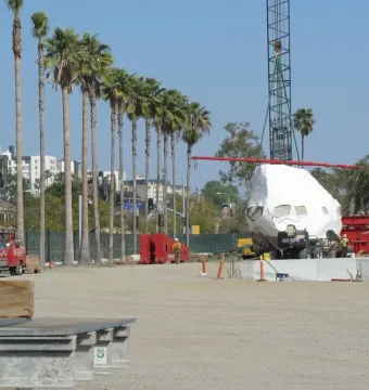 Levitated Mass boulder wrapped in white plastic on a transport vehicle at a construction site.