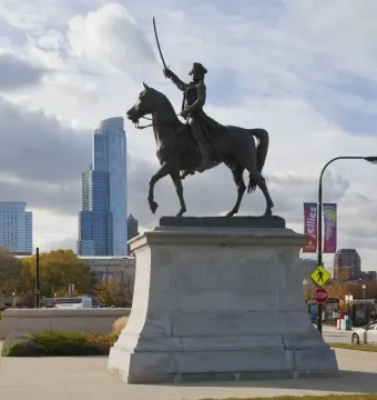 Tadeusz Kościuszko Monument, a dark bronze equestrian statue with the rider raising a sword above a stone pedestal, set against Chicago skyscrapers.