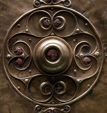 Close-up of the Battersea Shield showing a bronze central boss and swirling enamel patterns with red inlays.