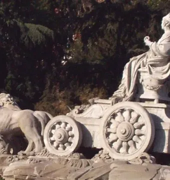 Cibeles Fountain sculpture with a crowned figure seated in a chariot pulled by two lions.
