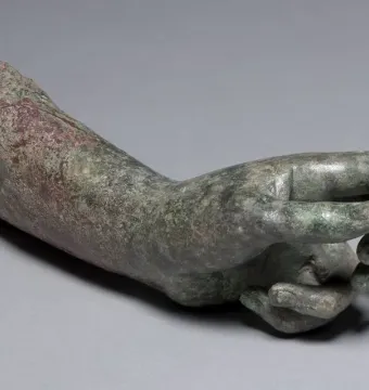 Weathered bronze arm and hand from The Cleveland Apollo with a green and reddish-brown patina.