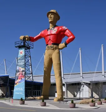The Golden Driller statue stands with one hand on an oil derrick and one hand on his hip in Tulsa.