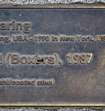 Bronze plaque for Keith Haring\'s Boxers with raised lettering and vertical text on the right side.