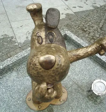 Bronze Reksio monument showing a stylized dog sculpture pointing its right arm.