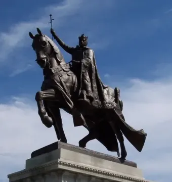 Apotheosis of St. Louis, a dark equestrian statue of a crowned figure holding a cross-topped scepter atop a stone pedestal