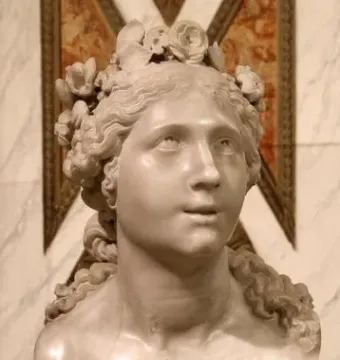 Blessed Soul, a white marble bust of a female figure with curly hair and a flower wreath, shown on a veined marble pedestal.