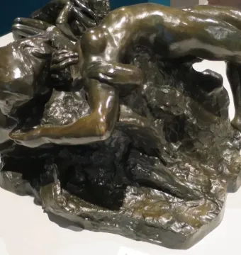 Illusions Received by the Earth, a dark bronze sculpture of two intertwined nude women on a rocky base.