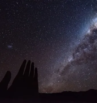 The Mano del Desierto sculpture silhouetted against a star-filled night sky and the Milky Way.