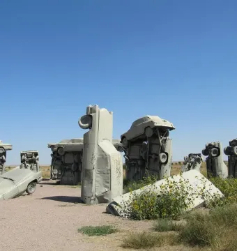 Inner circle of Carhenge with vintage cars painted gray and arranged in a sandy field.