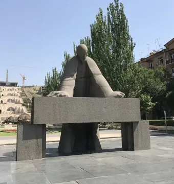Monument to Alexander Tamanyan in a paved plaza, with a large stone staircase rising behind it.