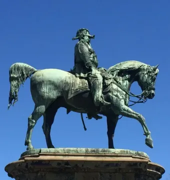 Victor Emmanuel II Monument showing a dark metal equestrian sculpture against a clear blue sky.
