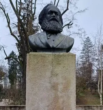 Karl Marx Monument showing a dark bust of a bearded man on a tall stone pedestal.