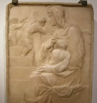 Madonna of the Stair relief showing a seated woman holding a child on her lap beside climbing figures in the background.
