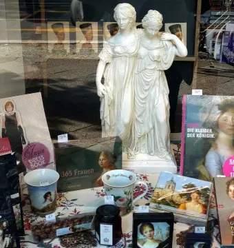 Princesses Monument statue displayed in a bookstore window among books and other merchandise.