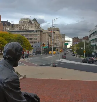 Seated Lincoln overlooks a brick-paved plaza toward a city intersection.