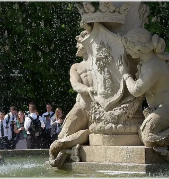Fountain of the Artichoke with stone figures holding a crest in a pool of water.