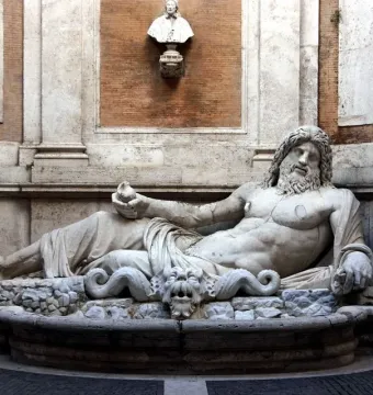 Marforio, a white marble reclining river god with a bearded upper body, set in an architectural niche.