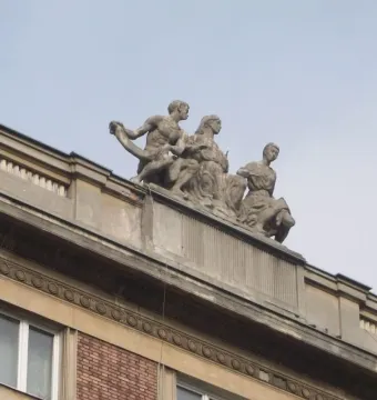 Stone sculpture of three figures representing Music, seen from below against a clear sky.