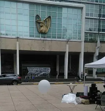 The Antimonumento 49 ABC stands on a building facade above a plaza with red flower petals and a white balloon on the ground.