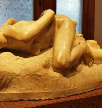 Malgré Tout sculpture of a reclining nude woman on a museum display stand