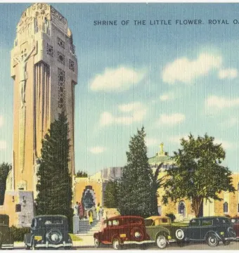 National Shrine of the Little Flower with a tall ornate tower, crucifix relief, and cars parked along the street below.