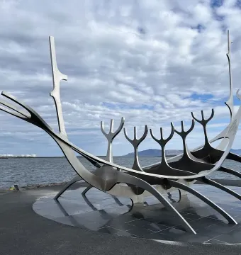 The Sun Voyager sculpture beside calm water under a cloudy sky.