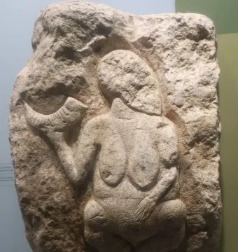 Venus of Laussel limestone relief showing a standing female figure holding a curved horn-like object.
