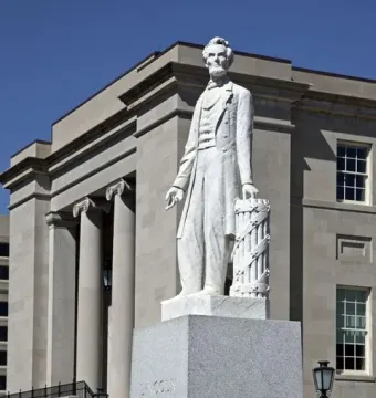 Abraham Lincoln statue on a stone pedestal in front of a classical courthouse building.