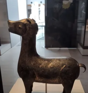 Ciervo de Madinat al Zahra, a dark patterned deer sculpture on a pedestal